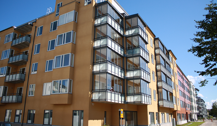 Utsidan av lägenheterna på Ängen i Örebro. Fastigheten består av gul puts och inglasade balkonger