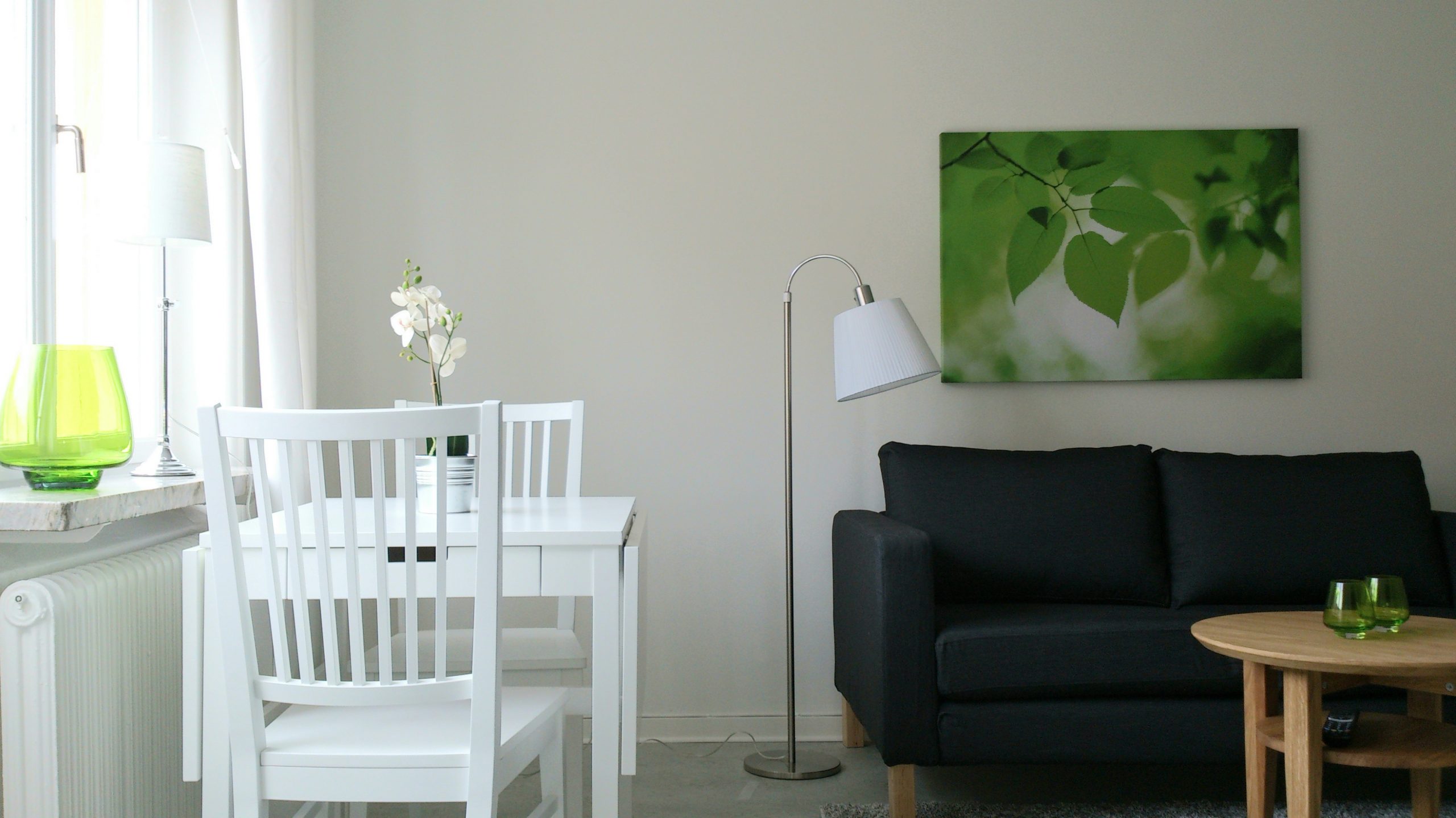 Möblerad lägenhet som Länsgården hyr ut. På bilden ser man ett vitt bord med två stolar, en svart soffa, en tavla, en lampa och ett soffbord i trä
